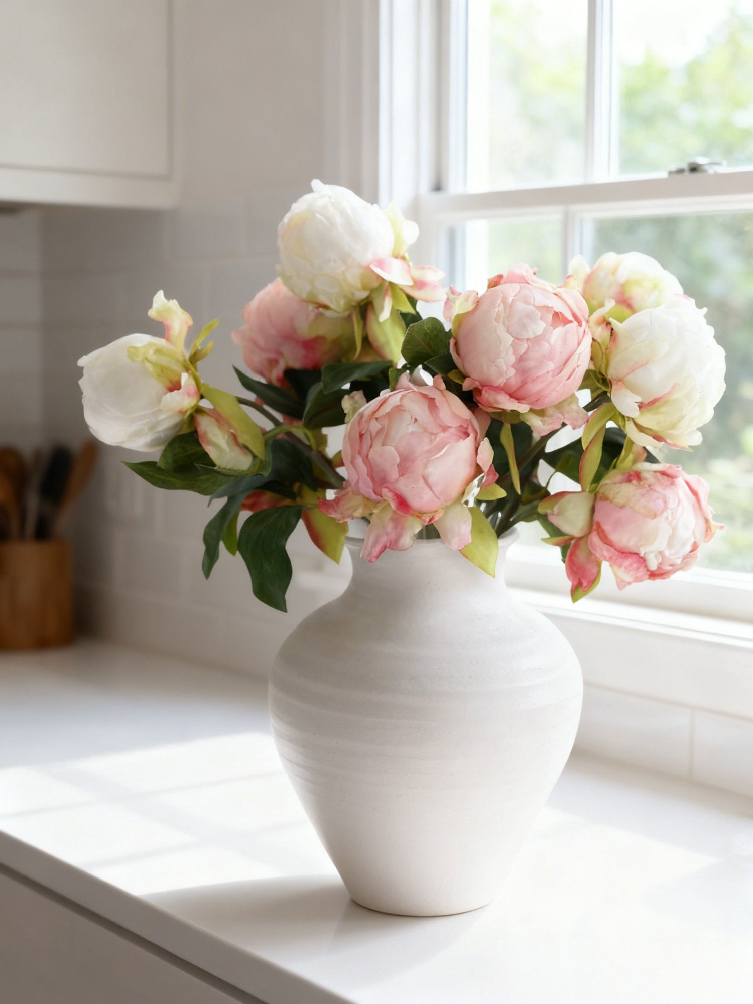 Faux peony buds arranged in a white vase