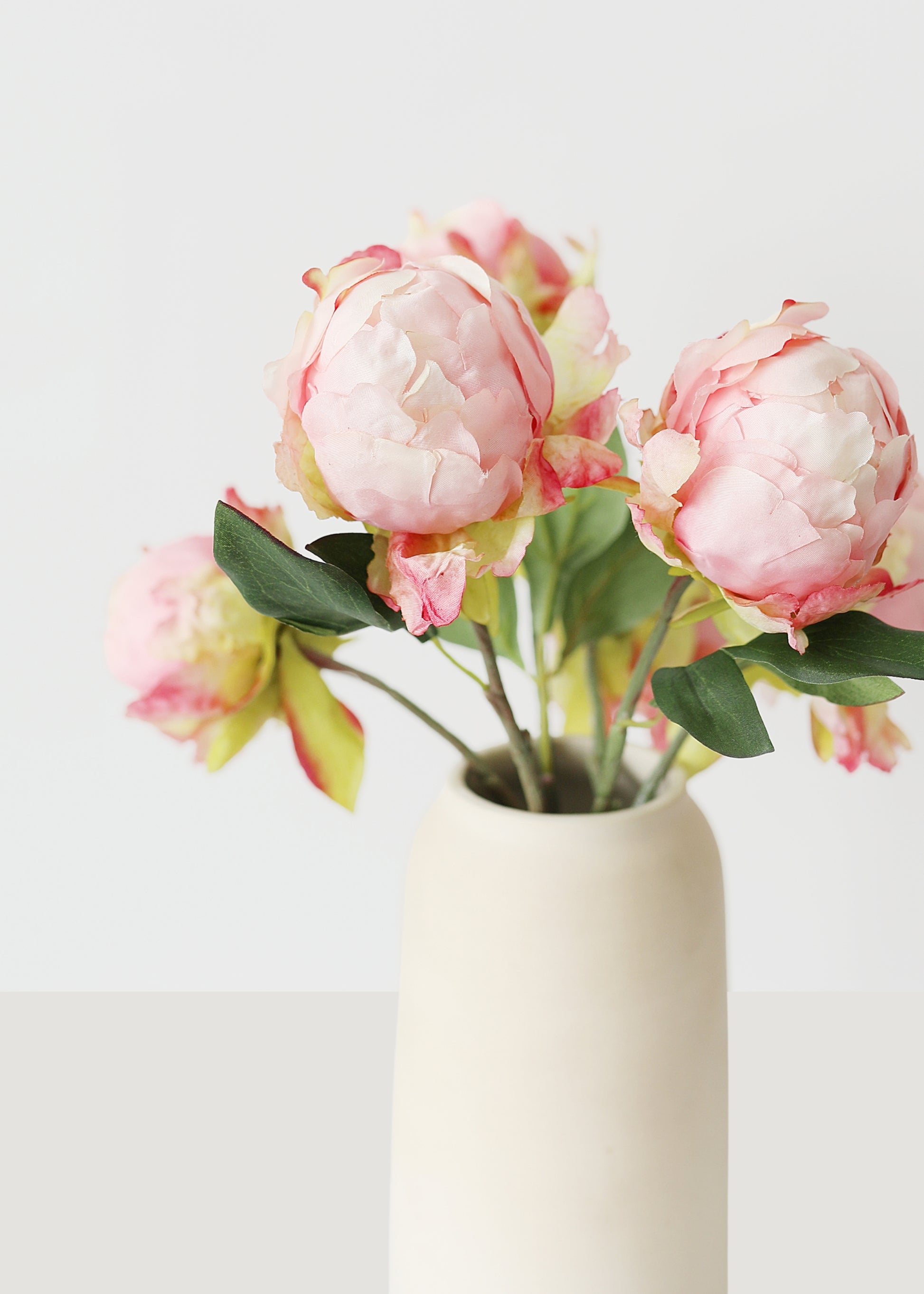 artificial peony buds arranged in a vase
