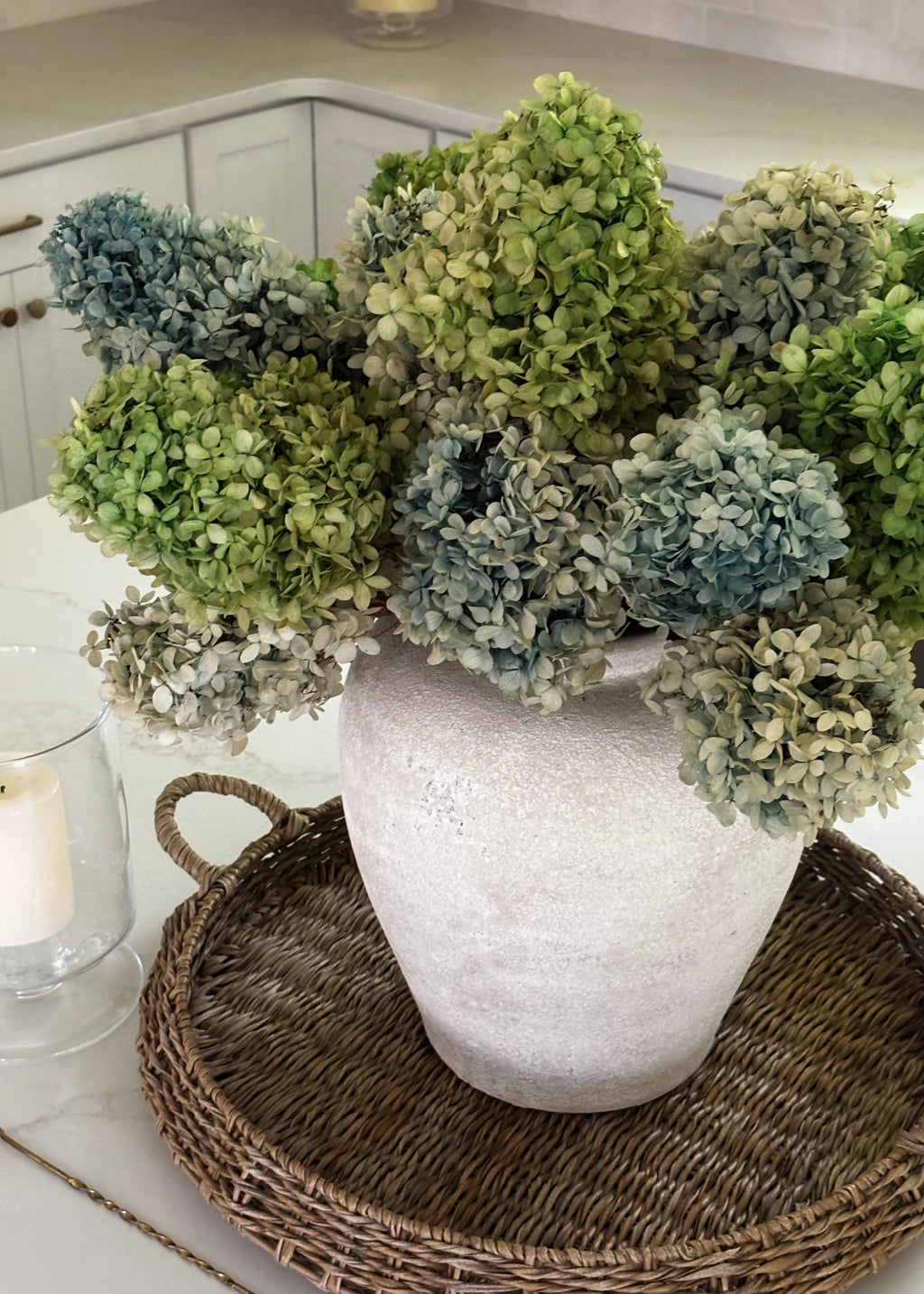 green and blue dried and preserved hydrangea blooms in a vase