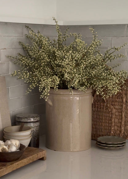 faux magnolia leaves and heather arranged in a handmade crock
