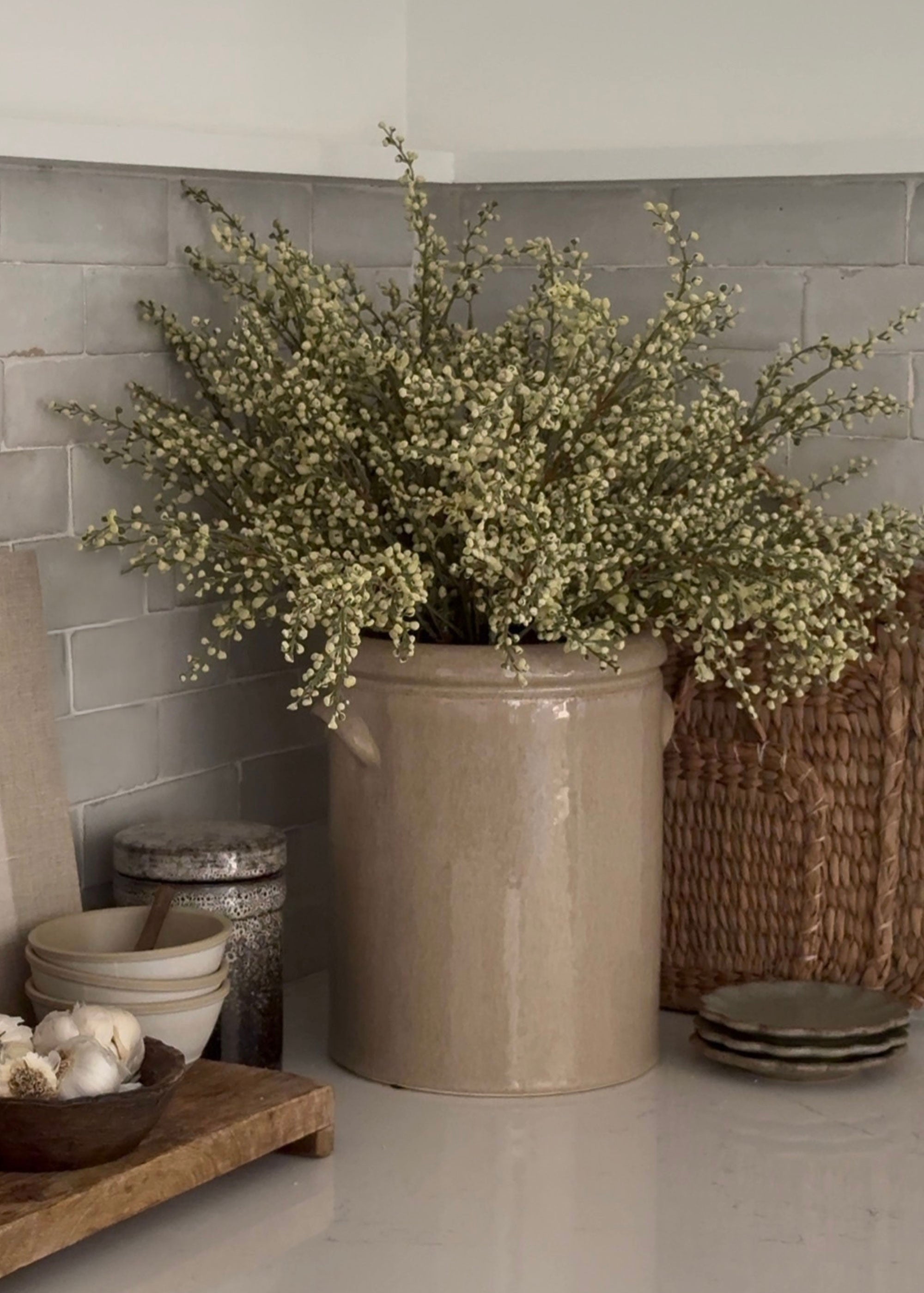 faux magnolia leaves and heather arranged in a handmade crock
