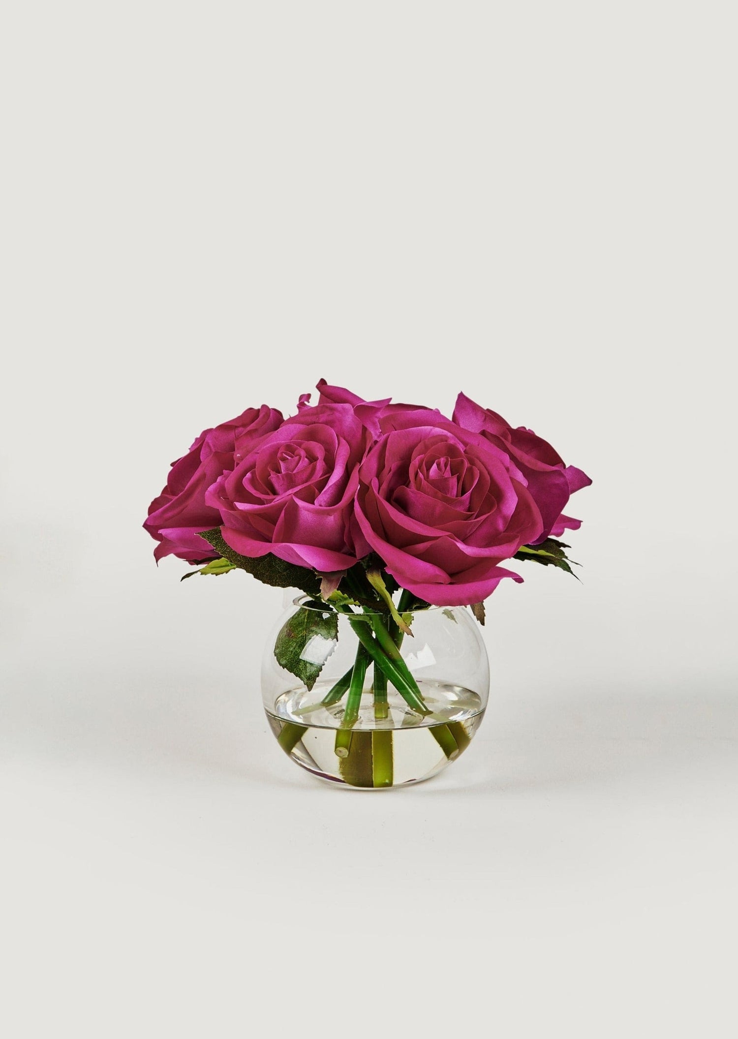 small faux arrangement of fuchsia real touch roses in round glass vase at afloral