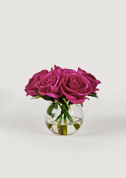 small faux arrangement of fuchsia real touch roses in round glass vase at afloral