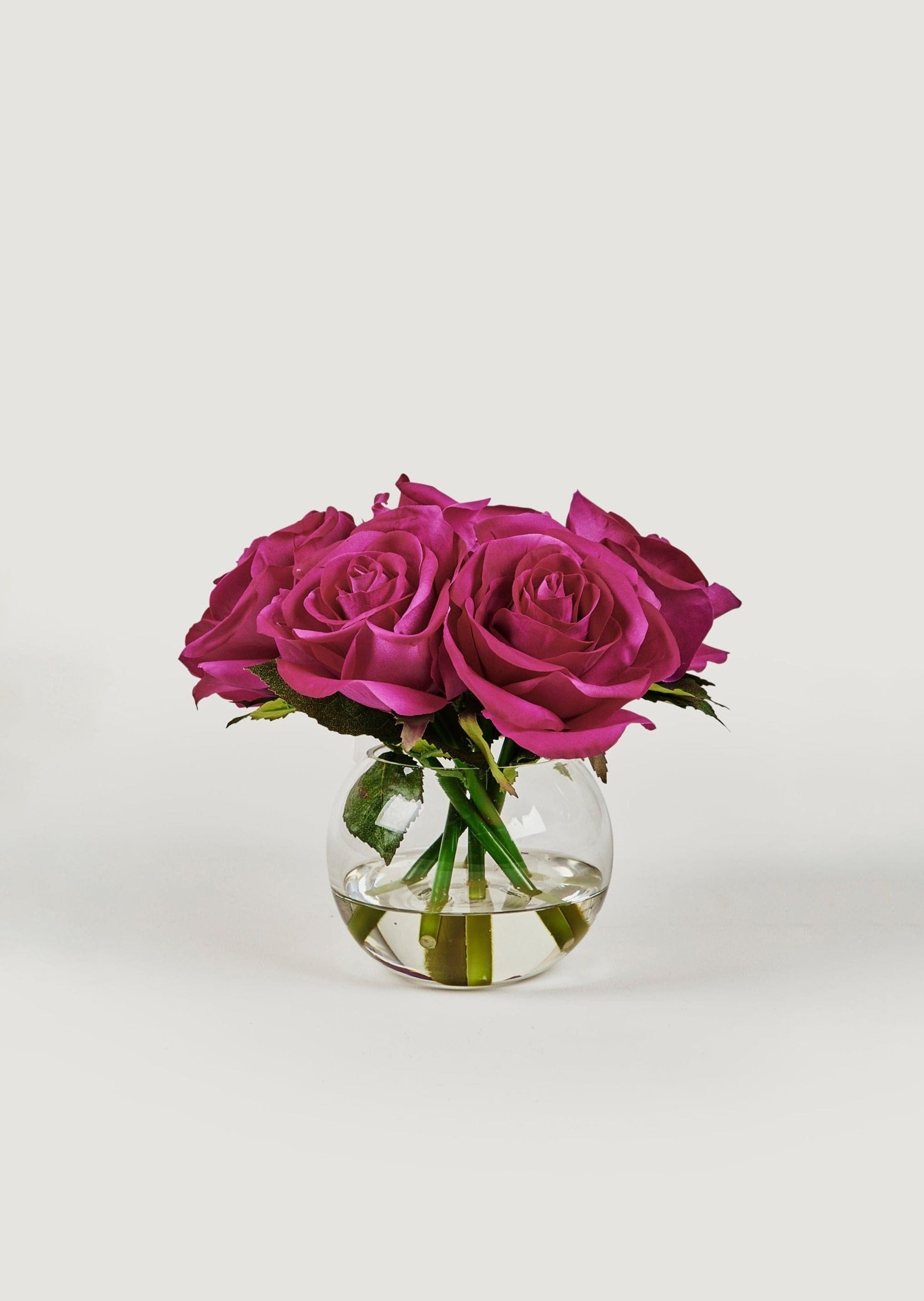 small faux arrangement of fuchsia real touch roses in round glass vase at afloral